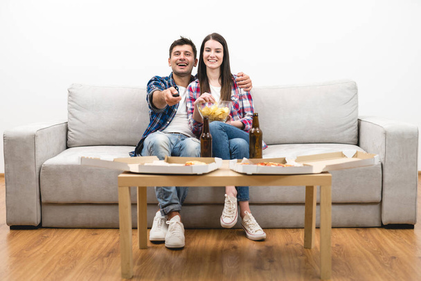 La coppia felice sul divano guardando la tv sullo sfondo della parete bianca
 - Foto, immagini