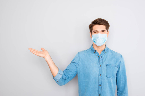 Portrait of handsome young successful businessman in blue shirt wear medical safety face mask , corona virus prevention protection concept, guy showing way or medicine product with hand and pointing - Foto, afbeelding