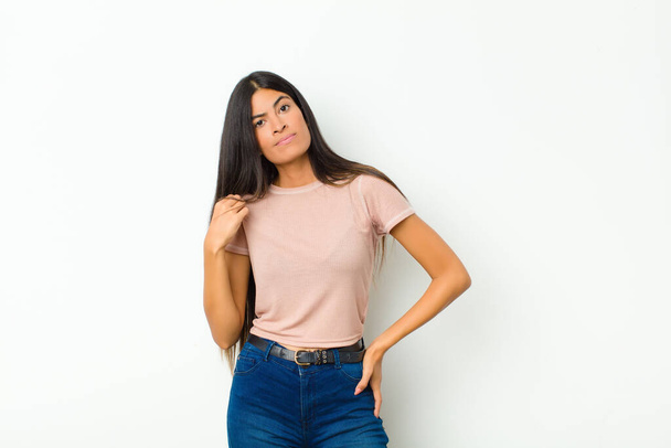 young pretty latin woman looking arrogant, successful, positive and proud, pointing to self against flat wall - Фото, зображення