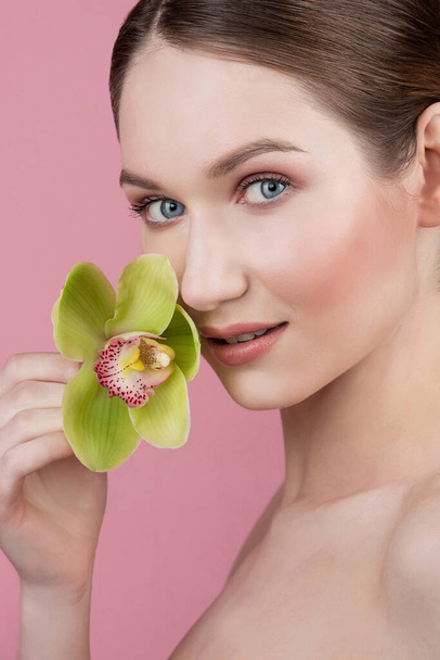Portrait of a young girl, flower girl, green archidea flower, pink background behind the model, natural makeup and beautiful skin - Foto, immagini