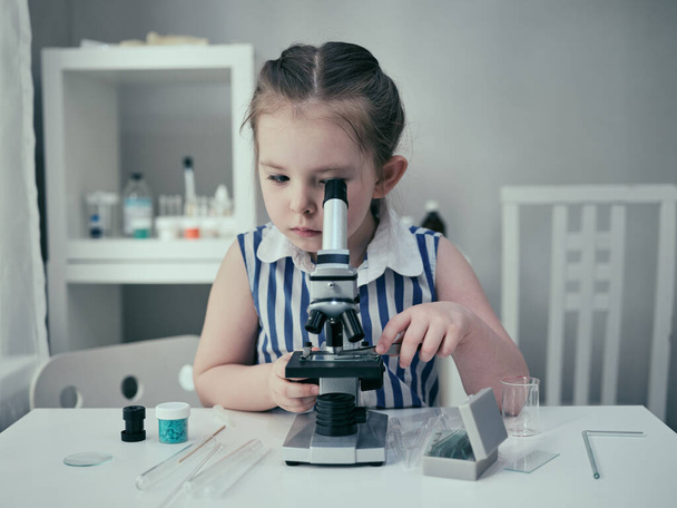 Маленькая девочка проводит научные эксперименты с химическими и биологическими продуктами в своей домашней лаборатории
. - Фото, изображение