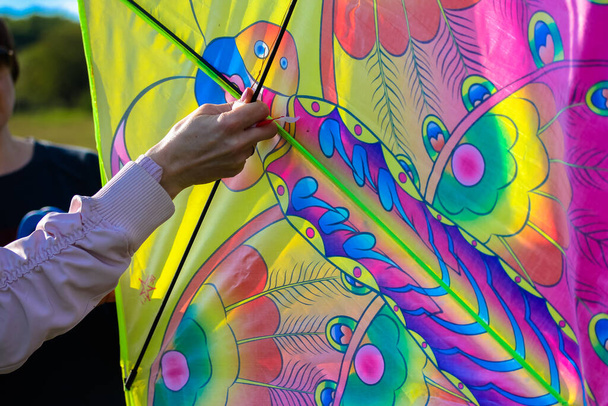 Ένα άτομο που κρατάει έναν πολύχρωμο χαρταετό - Φωτογραφία, εικόνα
