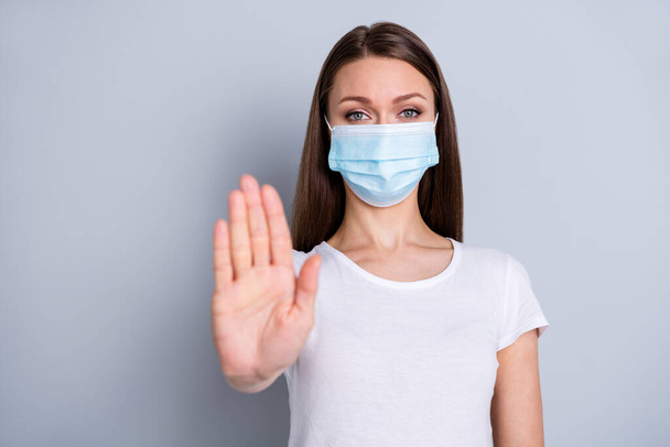 Photo of pretty serious lady keep social distance avoid people contacting hospital examination raise arm stand far away wear protect face mask t-shirt isolated grey color background - Foto, Imagen