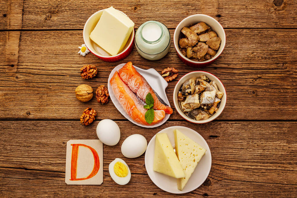 Foods containing vitamin D. Cheese, eggs, butter, nuts, milk, sardine, salmon, liver. Old wooden boards background - Φωτογραφία, εικόνα