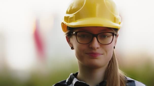 Portret van een jonge blanke vrouwelijke bouwkundige. Vrouw met bril en gele harde hoed - Video