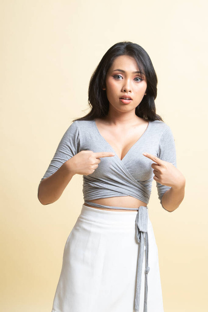 Young Asian woman point at herself ask why me   on beige background - Foto, imagen