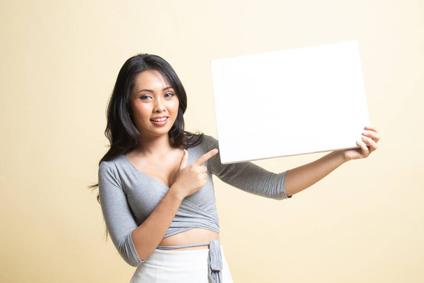 Young Asian woman point to  blank sign   on beige background - Фото, изображение
