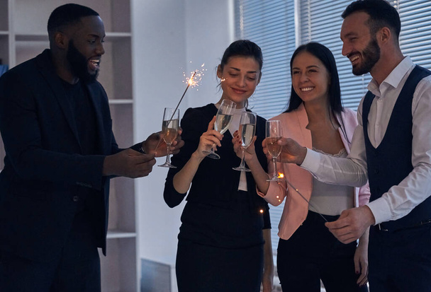 Die glücklichen Geschäftsleute, die Champagner trinken und Wunderkerzen in der Hand halten - Foto, Bild