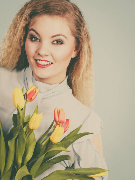 International women day, eight march. Beautiful portrait of pretty woman blonde hair with red yellow tulips, fashion make up. Mother day. Toned image - 写真・画像