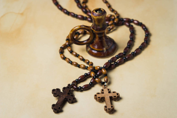  Religion concept. Christian religion. Two wooden crosses on wooden chains. Between the crosses is a candlestick. Crosses lies on a background of old paper. - Photo, Image