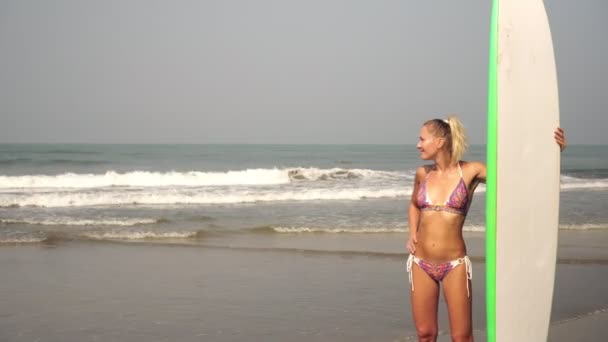 Молода сексуальна жінка серфінгує в сонячний день на пляжі. Дівчина з дошкою для серфінгу на морі
. - Кадри, відео