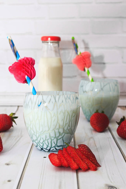 Kefir, leite, iogurte em garrafa e óculos azuis sobre fundo branco whith morango e coquetel palhas
. - Foto, Imagem