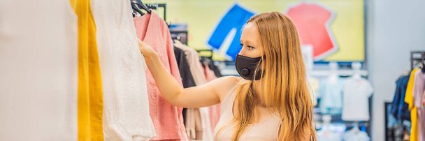 Woman in a clothing store in a medical mask because of a coronovirus. Quarantine is over, now you can go to the clothing store BANNER, LONG FORMAT - Photo, Image