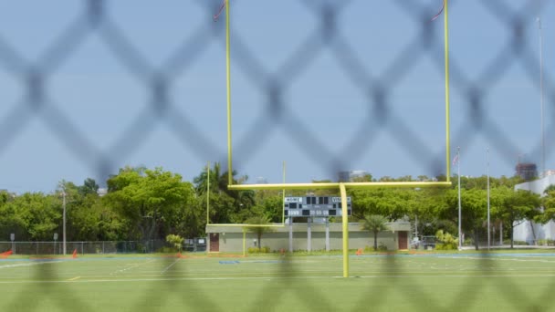 Campo de juego de fútbol vacío disparado a través de una cerca de eslabones de cadena 6k
 - Metraje, vídeo