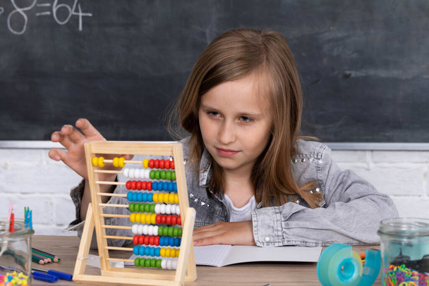 Abacus para adicionar números diferentes. A menina em uma lição de matemática acrescenta no ábaco. Método de contagem antiga
. - Foto, Imagem