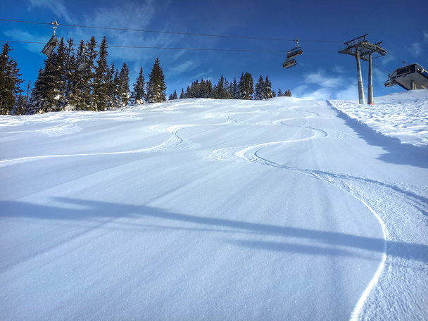 Three single traces at ski slope underneath a chairlift in the Austrian alps against blue sky - Foto, imagen