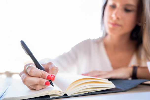 Attraktive junge Frau schreibt Geschäftsidee in ihr Notizbuch - Foto, Bild