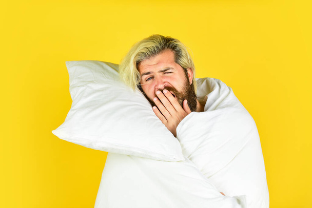 yawning male. bearded guy wear white blanket sleeping at hotel bedroom. bed rest while sick. man in underwear. Man wrapped in blanket the bathroom. handsome man in the morning - Photo, image