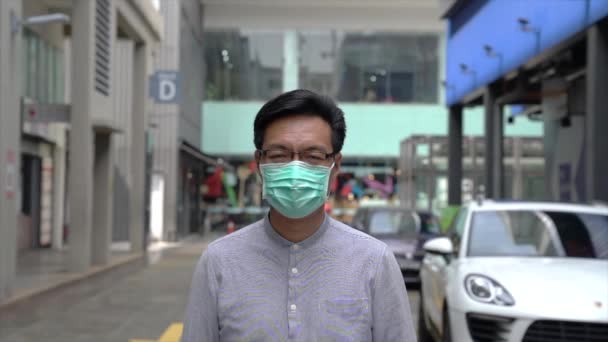 Asian Businessman wearing medical face mask walking in the city. Protection from coronavirus or pandemic. Lifestyle or new normal concept. - Filmagem, Vídeo