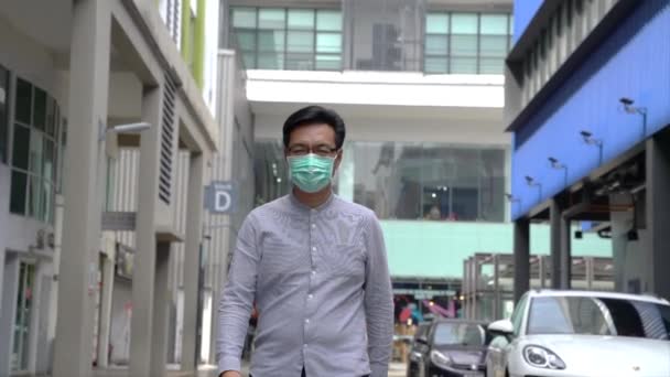 Asiatico uomo d'affari indossa maschera medica a piedi in città. Protezione da coronavirus o pandemia. Stile di vita o nuovo concetto normale
. - Filmati, video