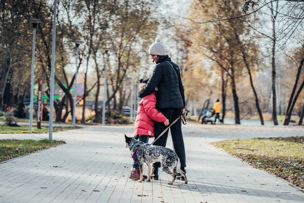 Happy mother and her daughter walk with dog in autumn park - Fotó, kép