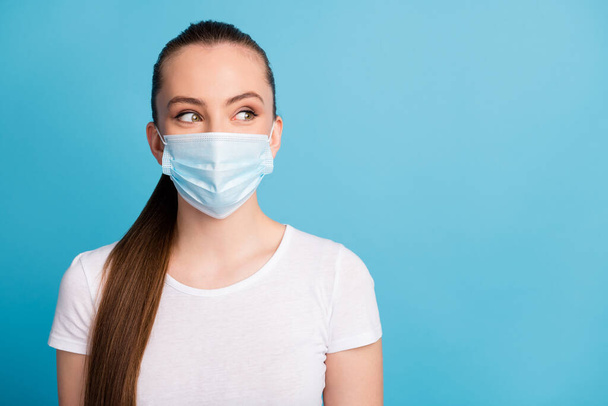 Closeup photo of pretty young lady look side empty space keep social distance not contacting people funny expression wear protect face medical mask white t-shirt isolated blue color background - Photo, image