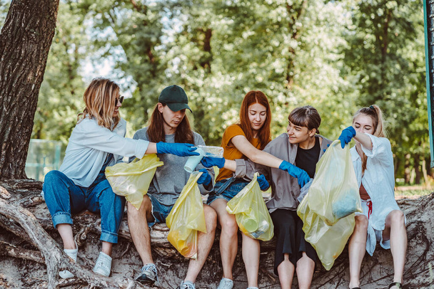 Grupo de activistas amigos recogiendo residuos plásticos en el parque. Conservación ambiental
. - Foto, imagen