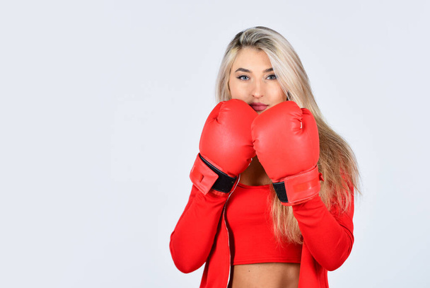 confident young sportswoman posing in boxing gloves. beautiful woman with red boxing gloves. young sports woman in tracksuit and boxing gloves. blond boxer woman. kick off - 写真・画像