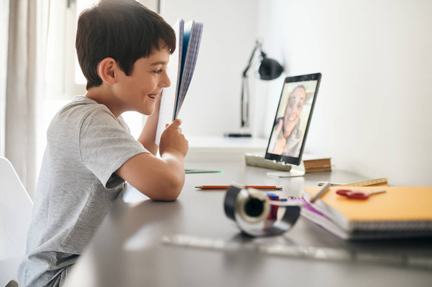 Gelukkige kleine jongen die online lessen thuis volgt. Schoolonderwijs en sociale afstand tijdens quarantaine - Foto, afbeelding