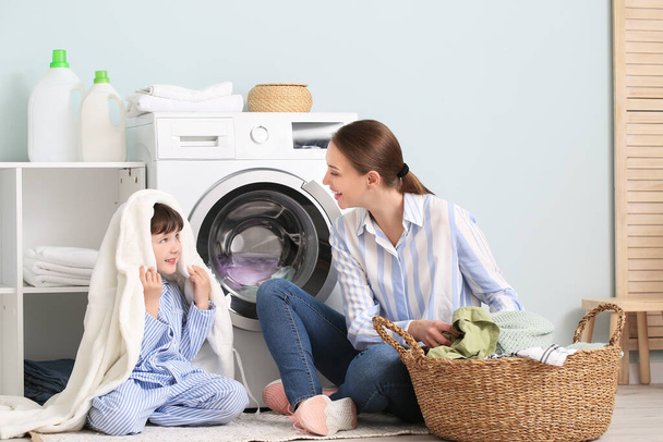 Jeune femme avec son petit fils faisant la lessive à la maison
 - Photo, image