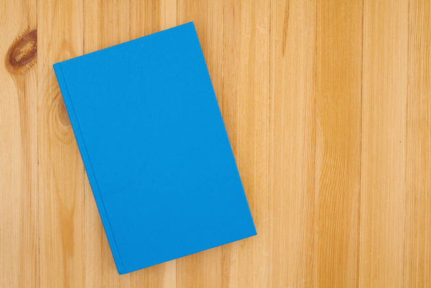 Sininen kovakantinen kirja männyn puupöydällä, jossa on kopiotila koululle tai lukuviesti tai mallinnus - Valokuva, kuva