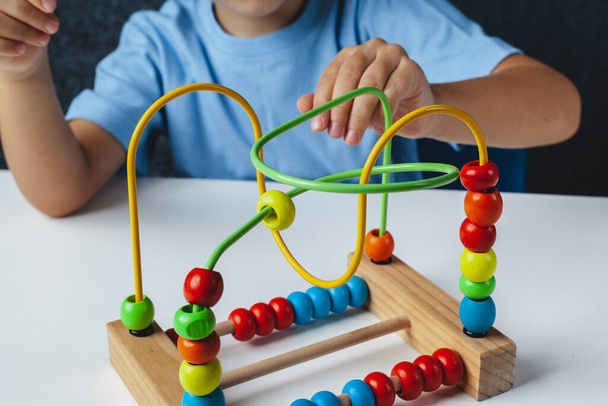 Kind spielt Montessori-Spiel. Kind sammelt Holzspielzeug-Sortierer. Mehrfarbige geometrische Formen, Kreis, Quadrat, Dreieck, Rechteck. - Foto, Bild