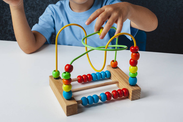 Niño juega juego Montessori. Niño recoge clasificador de juguetes de madera. Forma geométrica multicolor, círculo, cuadrado, triángulo, rectángulo. - Foto, Imagen