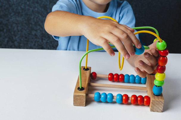 Niño juega juego Montessori. Niño recoge clasificador de juguetes de madera. Forma geométrica multicolor, círculo, cuadrado, triángulo, rectángulo. - Foto, imagen