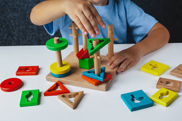 子供はモンテッソーリゲームをプレイします。子供は木製のおもちゃの選別機を集める。多色幾何学的形状,円,正方形,三角形,長方形. - 写真・画像