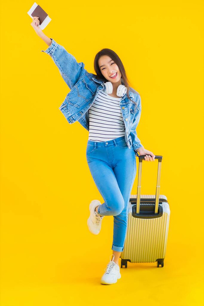Porträt schöne junge asiatische Frau reisen und Freizeit mit Gepäcktasche und Pass, Bordkarte auf gelbem Hintergrund isoliert - Foto, Bild