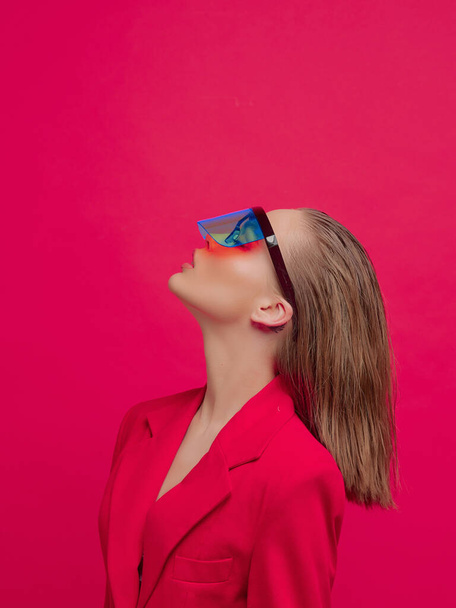 Крутая стильная девушка с модной прической и стильными очками с большим стеклом позирует на ярко-красном фоне
 - Фото, изображение