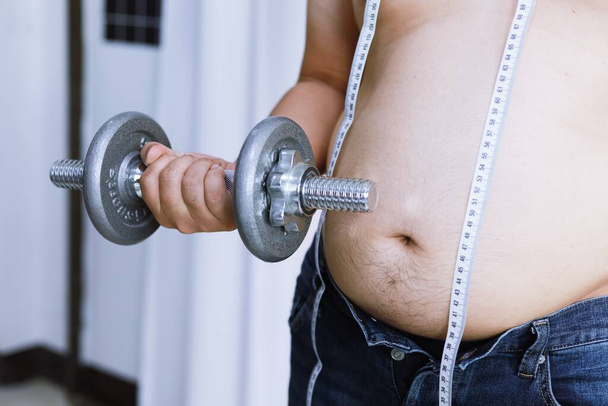 Túlsúlyos ember gyakorlása súlyemeléssel egy súlyzóval - Fotó, kép