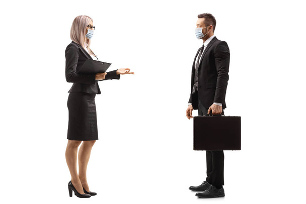 Full length profile shot of a businesswoman talking to a businessman and wearing protective face masks isolated on white background - Photo, Image