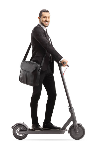 Full length shot of a professional man in a suit riding an electric scooter isolated on white background - Photo, image