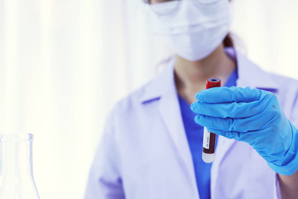 Scientist holding Coronavirus covid-19 infected blood sample tube. DNA testing of the blood in the laboratory with blood sample collection tubes and syringe Coronavirus Covid-19 vaccine research - Φωτογραφία, εικόνα