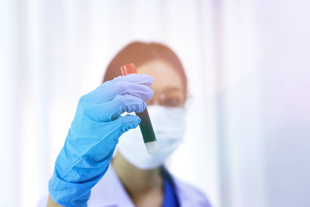 Wetenschapper die Coronavirus covid-19 geïnfecteerde bloedstalen buis vasthoudt. DNA-test van het bloed in het laboratorium met bloedmonsterverzamelbuizen en injectiespuit Coronavirus Covid-19 vaccinonderzoek - Foto, afbeelding