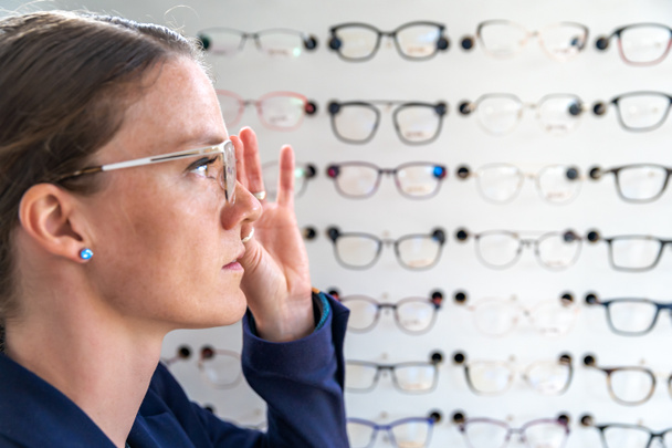 the glasses are selected and tested by a woman in an optics store. copy space - Photo, Image