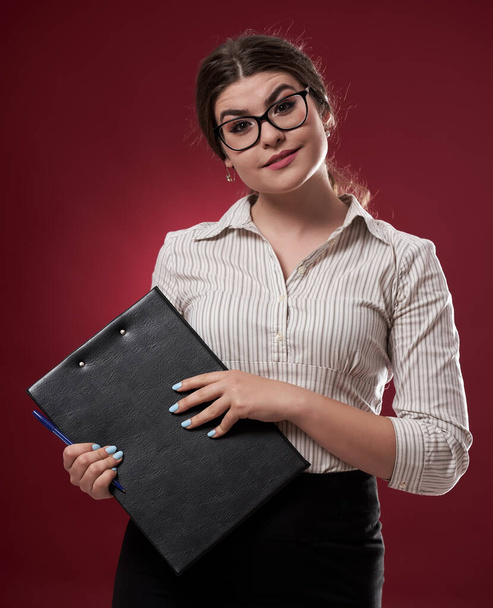Joven mujer de negocios caucásica con un portapapeles sobre fondo rojo
 - Foto, imagen