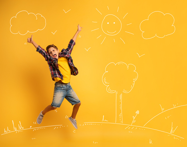 Mutlu ve duygusal çocuk sarı bir arkaplanda zıplıyor. - Fotoğraf, Görsel
