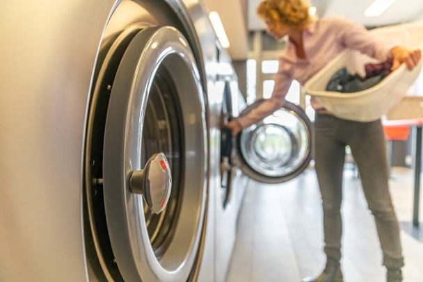 a inserir roupas sujas na máquina de lavar roupa da lavandaria. borrado com espaço de cópia
 - Foto, Imagem