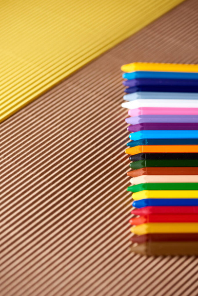 kleurrijke potloden op een geel en bruin karton - Foto, afbeelding