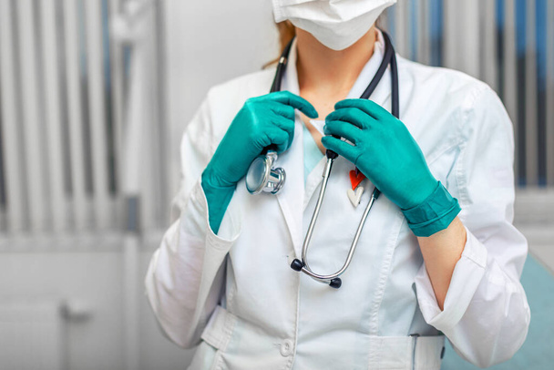 Los médicos entregan una bata blanca sosteniendo un fonendoscopio en el fondo de una sala de hospital. Medicina, salvavidas, médicos generales
. - Foto, imagen