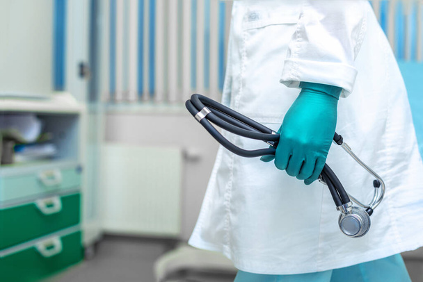 Os médicos entregam um casaco branco segurando um fonendoscópio no fundo de uma enfermaria do hospital. Medicina, salvamento de vidas, clínicos gerais
. - Foto, Imagem