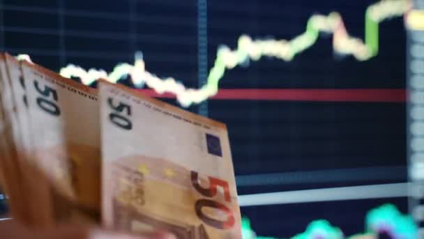 Weltbörsen stürzen ab, Papierwährungen verlieren an Wert, Menschen zählen Euroscheine und werfen sie vor dem Hintergrund von Auf- und Abwärtstrenddiagrammen nach unten. Finanzkrise und Wirtschaftskrise - Filmmaterial, Video